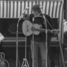 Photo de Bob Dylan avec sa guitare se préparant à chanter sur scène